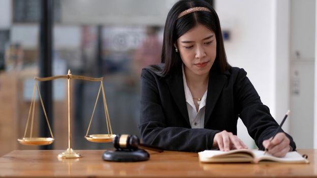 Business and lawyers discussing contract papers with brass scale on desk in office. Law, legal services, advice, justice and law concept picture with film grain effect.