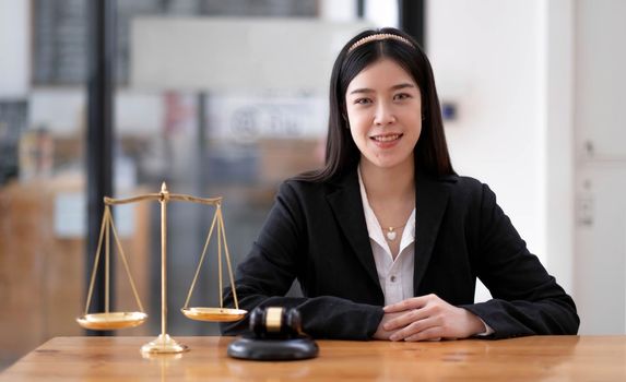 Attractive young lawyer in office Business woman and lawyers discussing contract papers with brass scale on wooden desk in office. Law, legal services, advice, Justice and real estate concept..