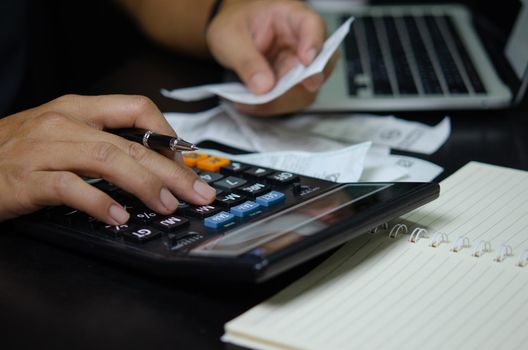 Man hand holding pen and calculator bills or tax receipt. business finance concept.
