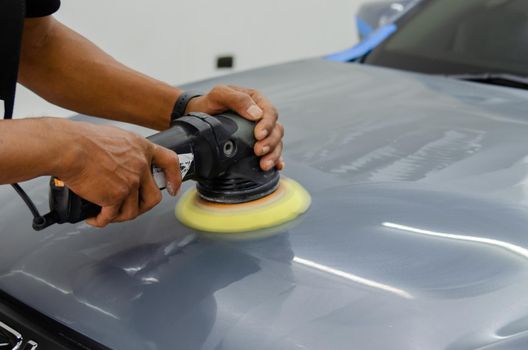 Man holding tool polish mechanic auto repair detailing hood car scratch maintenance in garage carwash job.