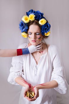 A young Ukrainian woman during the war with a yellow blue wreath of bullets and blood on a white background close-up. Russia attacked Ukraine in 2022