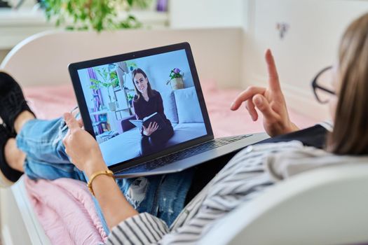 Online therapy meeting of woman with psychologist. Female lying on couch at home talking with counselor, using laptop for conference call video chat. Technology, psychology, youth, mental health