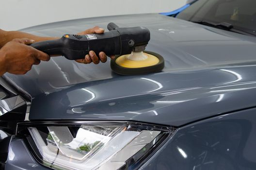 Man holding tool polish mechanic auto repair detailing hood car scratch maintenance in garage carwash job.