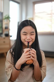 Smiling asian girl drinking iced bubble milk tea.