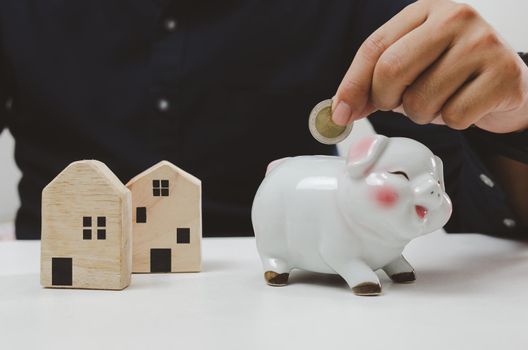 Hand holding coin saving piggy bank finance investment loan house. business economy home estate property concept.