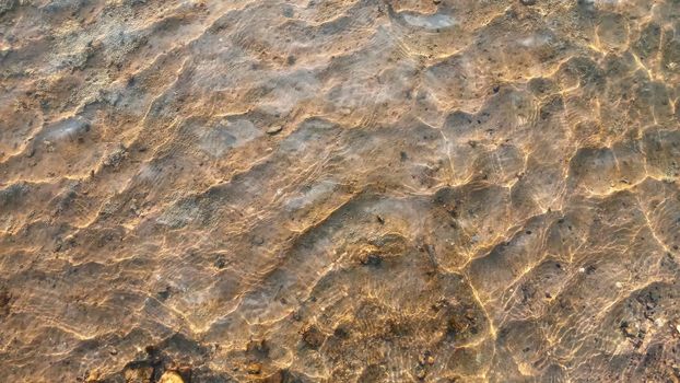 Top view on colorful pebbles covered by water. Close up view of smooth round pebble stones on the beach.