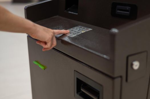 Faceless woman dialing bank card pin at ATM