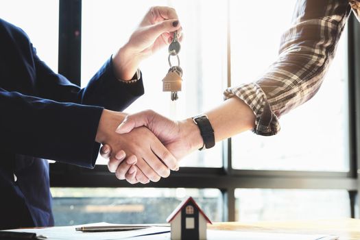 Focus on the congratulatory handshake. The real estate agent agrees to buy the home and hand the keys to the customer at the agent's office. conceptual agreement