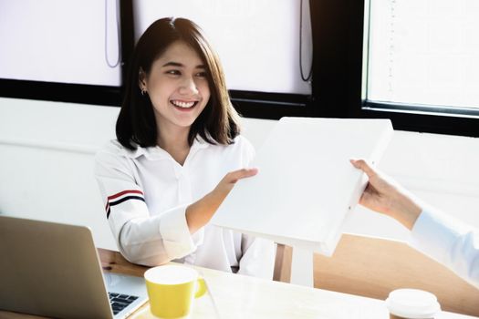 Two female company employees happily smiled at each other as they handed each other folders