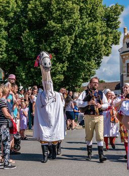 Straznice, Czech Republic - June 25, 2022 International Folklore Festival. People in folk costumes in a procession with a horse mask