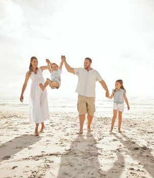 Carefree caucasian family walking and having fun together on the beach. Parents spending time with their daughters while on holiday. Little siblings holding hands with their parents on vacation.