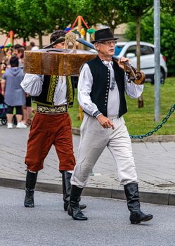 Straznice, Czech Republic - June 25, 2022 International Folklore Festival. Two men in folk costumes carry kontarabas