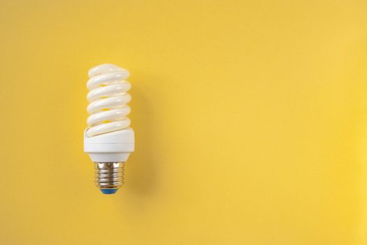 Energy saving light bulb on a yellow background. Economical consumption of electricity. The concept of nature conservation