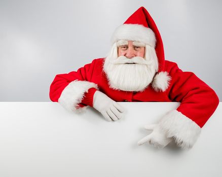 Santa Claus points to an empty white space. Promotional offer for Christmas