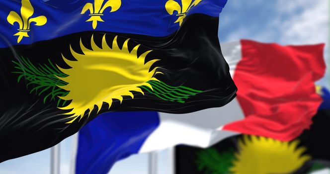 National flags of Guadeloupe waving the with the flag of France on a clear day. Guadeloupe is an archipelago and overseas department and region of France in the Caribbean