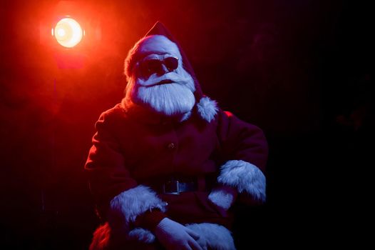 Santa claus in sunglasses in neon light on a black background. Christmas party