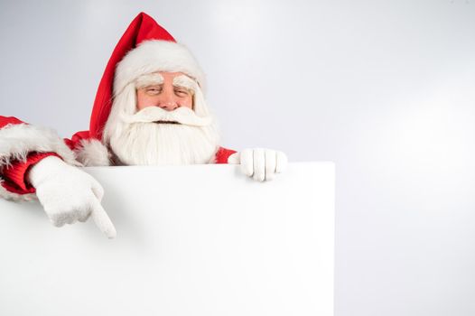 Santa Claus points to an empty white space. Promotional offer for Christmas