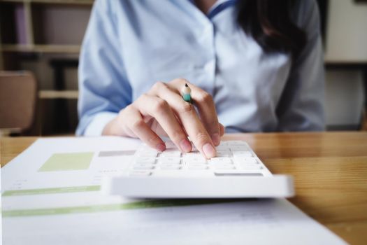 Business woman using calculator to review balance sheet annual using document to calculating budget. audit and Check integrity before investment concept