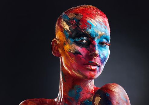 The world would be boring in black and white. an attractive young woman posing alone in the studio with paint on her face