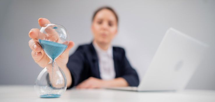 Business woman flipping an hourglass at her desk