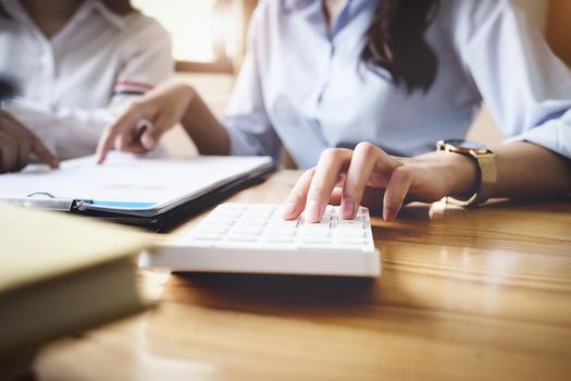 focus hand using calculator, Two young business executives are discussing to change their business concept to increase profits and the strength of their business with using calculator for work