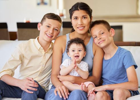 Portrait of a multiracial family at home.Mother with her adoptive sons. Young mother relaxing with her children. Mixed race family relaxing together at home. Boys spending time with their parent