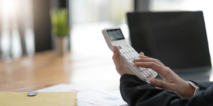 Close-up of business woman hands using a calculator to check company finances and earnings and budget..