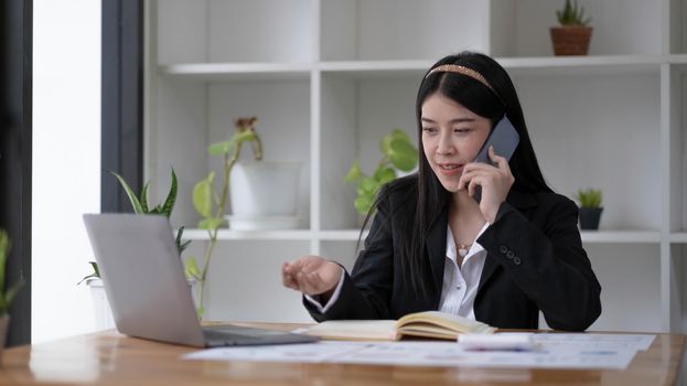 Asian businesswoman talking on the phone with customer in the office..