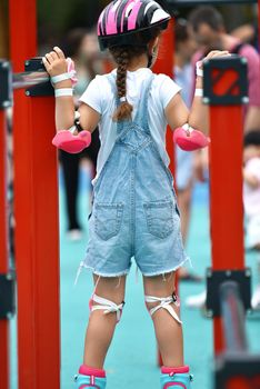 selective focus. Little girl child in protective clothing helmet knee pads elbow pads with rollers. girl 6 years old on the playground. crossfit for kids. Active girl goes in for traumatic sports.