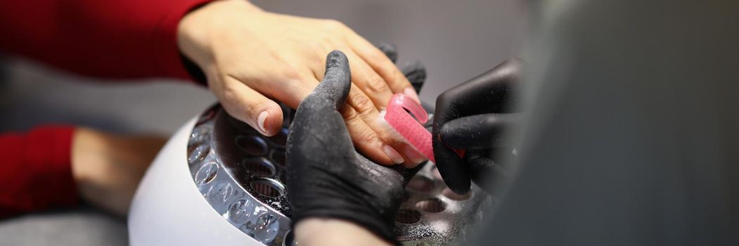 Close-up of nail master cleaning clients hands from dust with special brush. Woman on beauty procedure in luxury salon. Wellness, self love, care concept