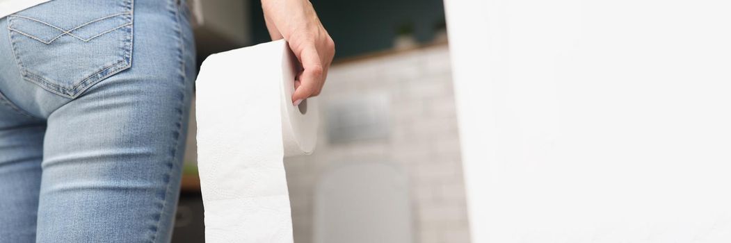 Close-up of woman hold white clean toilet paper roll in hands, enter toilet room. Constipation or diarrhea problem, nature calls. Hygiene, bathroom concept