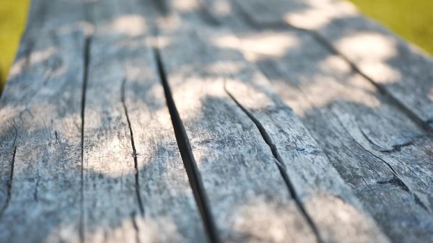 An old wooden table in a summer garden with rays of sunshine