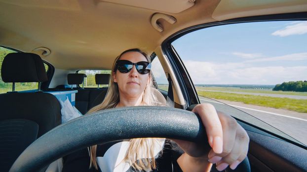 A young woman in a good mood behind the wheel of a car