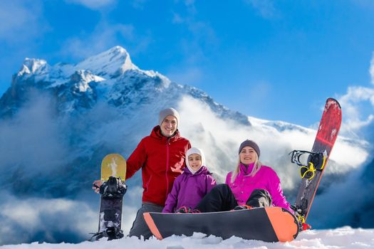 family and snowboard on snowy mountain.