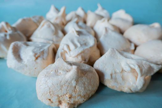 Homemade french milk-colored meringues on bluet paper. flatley composition: delicious homemade meringues on craft paper