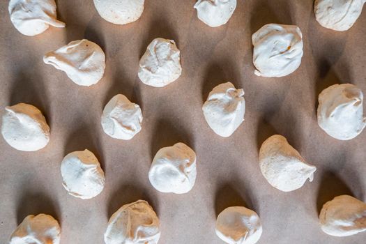 Sweets on a beautiful pastel surface in a minimalist style. Homemade meringues are lying on the baking paper. High quality photo
