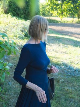 senior fit elegant lady dressed in blue and wearing sunglasses enjoying nature in summer
