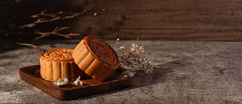 Tasty Chinese mooncakes decorating with dried flower on grey stone background. Chinese Mid autumn festival celebration.