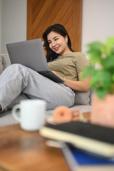 Casual young woman ordering food online or chatting in social networks on laptop computer.