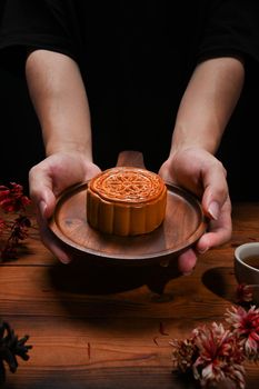 Hands holding wooden tray with Chinese traditional mooncakes. Mid Autumn festival and Chinese traditional festival.