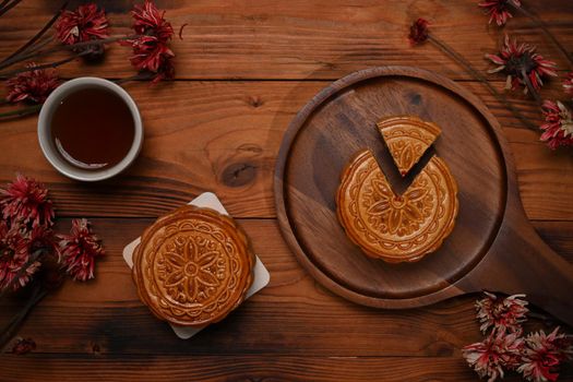 Top view, Traditional Chinese mooncakes, tea and dried flower on rustic wooden background.
