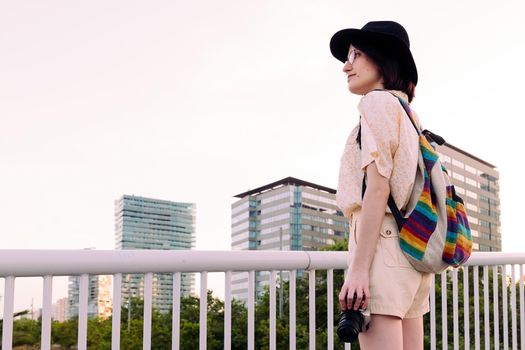 beautiful young tourist woman with backpack in the city with a vintage camera, concept of youth and traveler lifestyle, copy space for text