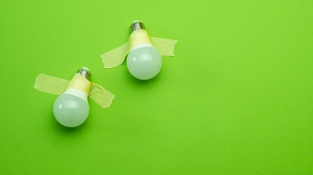 Two lamps lightbulb attached with tape on green background. Concept of creativity and brainstorm ideas