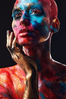 Art captures the soul. an attractive young woman posing alone in the studio with paint on her face and body