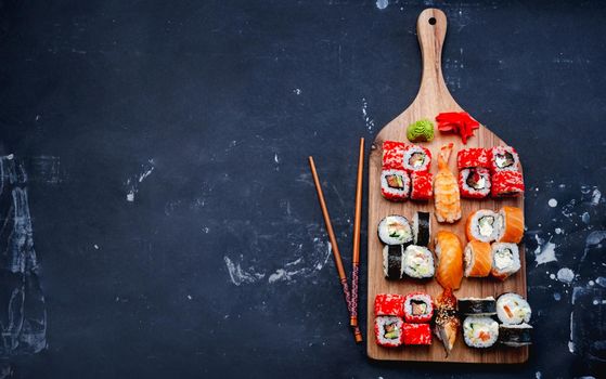 Colorful sushi maki set on wooden desk served with chopstick, ginger and wasabi. Oriental japanese healthy cuisine with raw fish and rice