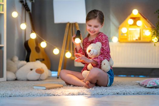 Happy little girl playing with shadows in children's room