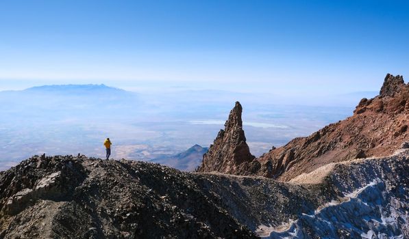 Hiker ascending top of volcanic mountain in daytime