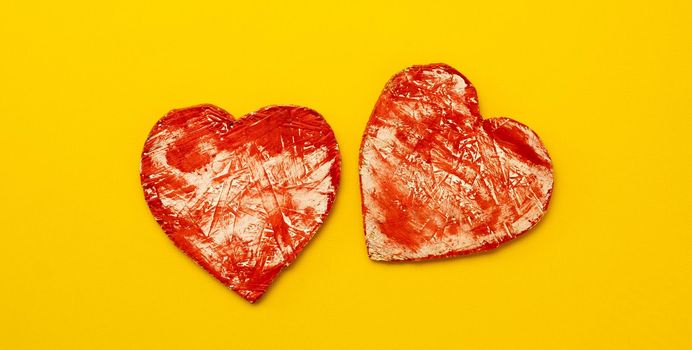Two red hearts isolated on yellow background with copy space. Concept of love, hapiness and feelings. Abstract symbol of passion and togetherness