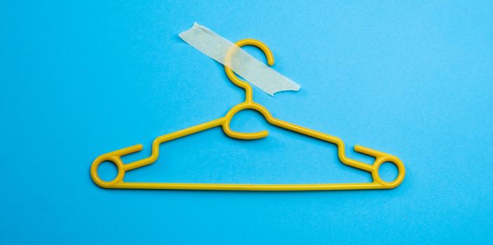 Plastic hanger with masking tape isolated on blue background with copy space. Concept of sales, fashion and e-commerce retail world. Equipment for clothes