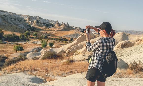 Rear view of woman tourist photographing canyon in Cappadocia, Turkey